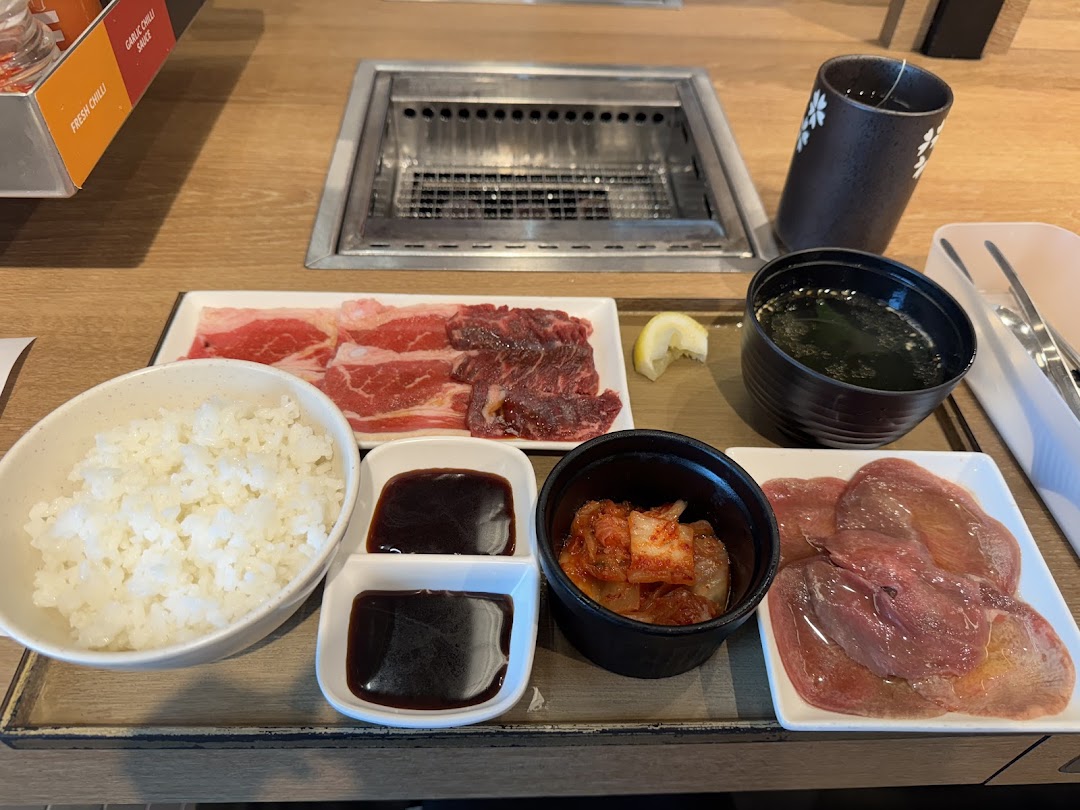 A delicious yakiniku meal set with raw beef, rice, soup, kimchi, and sauces, ready for grilling.
