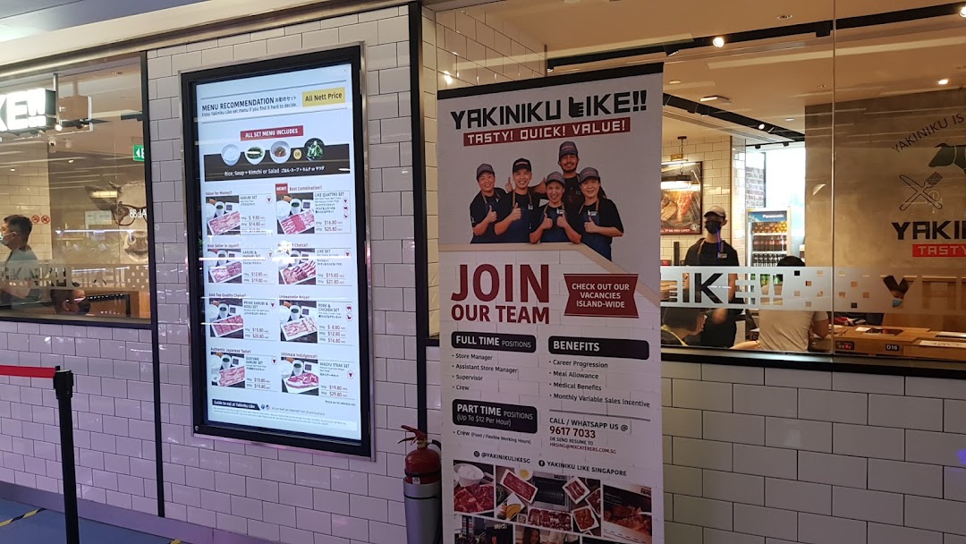 The exterior of Yakiniku Like, featuring a digital menu display and a recruitment banner.