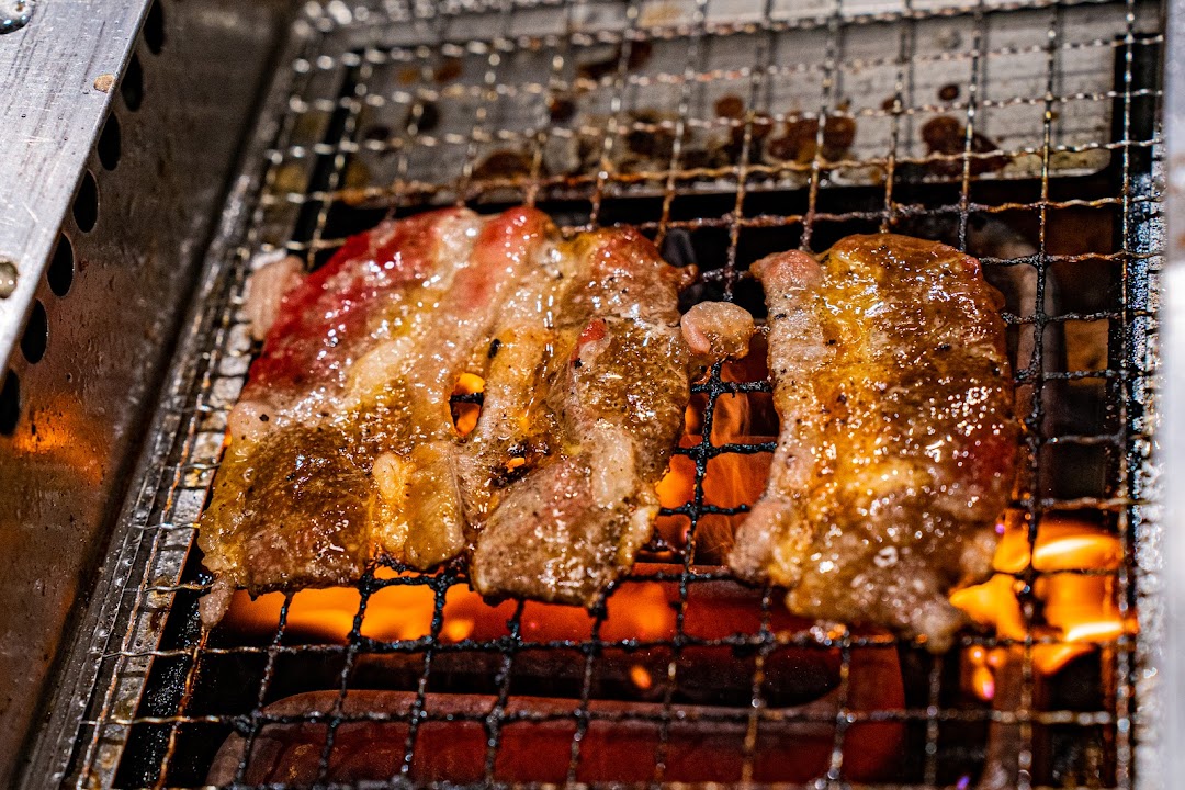 Close-up of sizzling yakiniku beef grilling over hot coals.