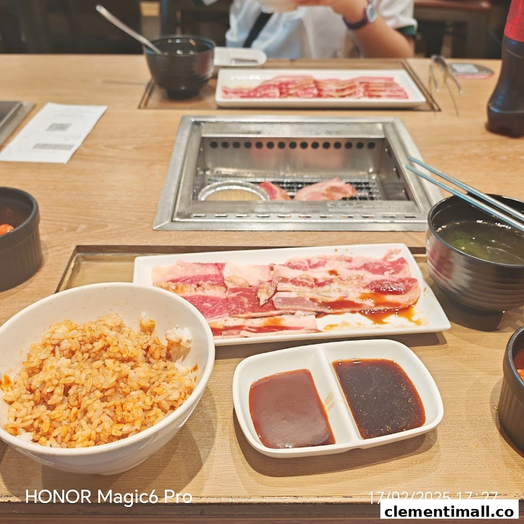 A close-up of a yakiniku meal featuring raw meat, rice, sauces, and a built-in grill at a table.