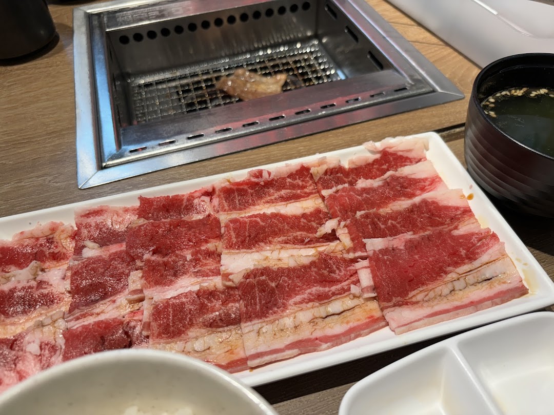 A plate of thinly sliced raw beef ready for grilling at a yakiniku restaurant table.