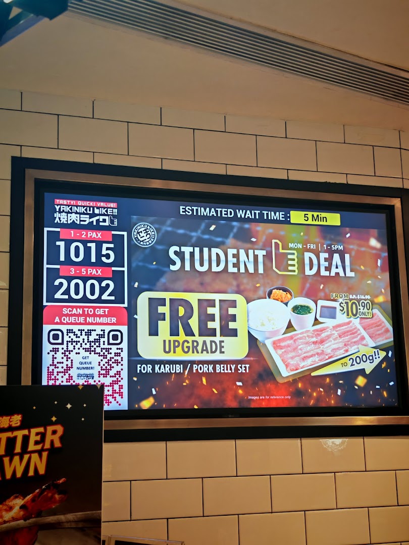 A digital display inside Yakiniku Like, showing queue numbers and a student deal for a free meat upgrade.