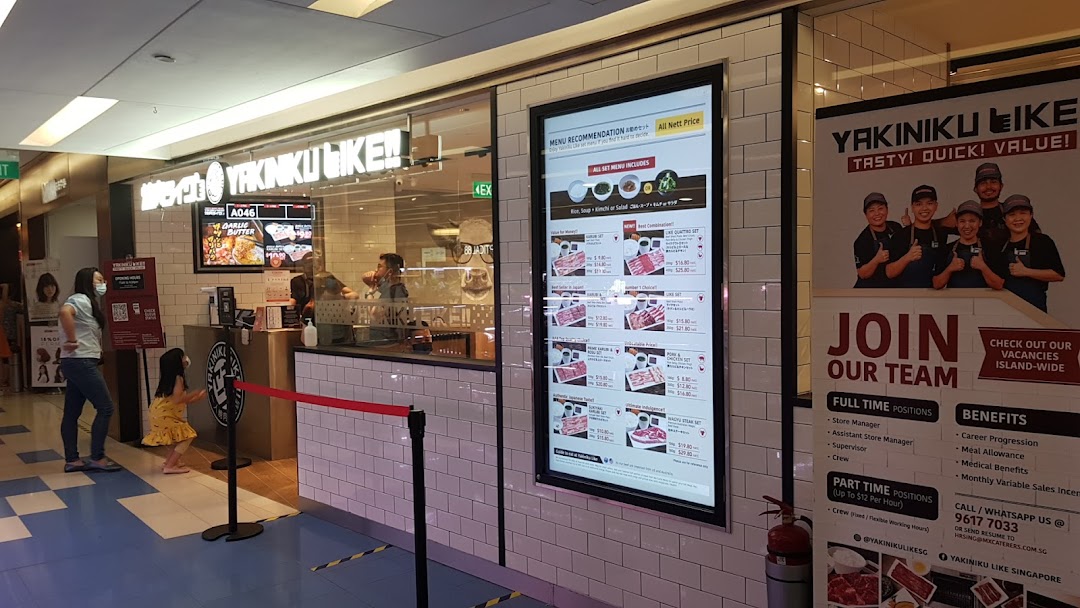 The shop front of Yakiniku Like, featuring a digital menu board and recruitment poster.