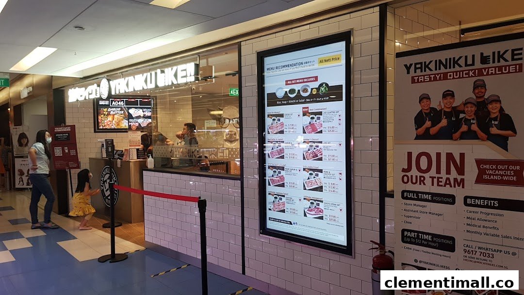 The shop front of Yakiniku Like, featuring a digital menu board and recruitment poster.