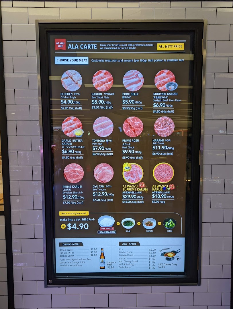 A digital menu board displaying various customizable meat cuts, drinks, and side dishes with prices.
