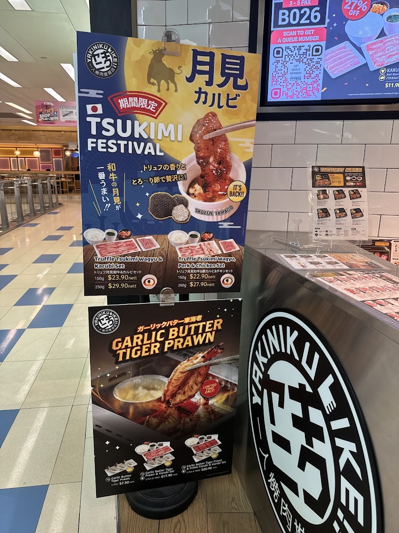 Promotional standees for Yakiniku Like, featuring Tsukimi Festival and Garlic Butter Tiger Prawn specials.