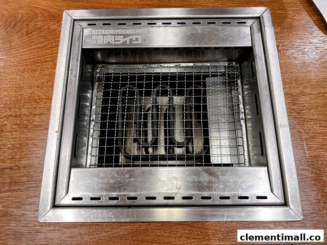 A close-up view of a clean, built-in yakiniku grill with a metal grate on a wooden table.