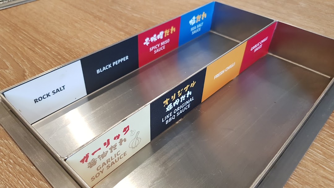 A close-up of a stainless steel condiment tray offering various sauces and seasonings.