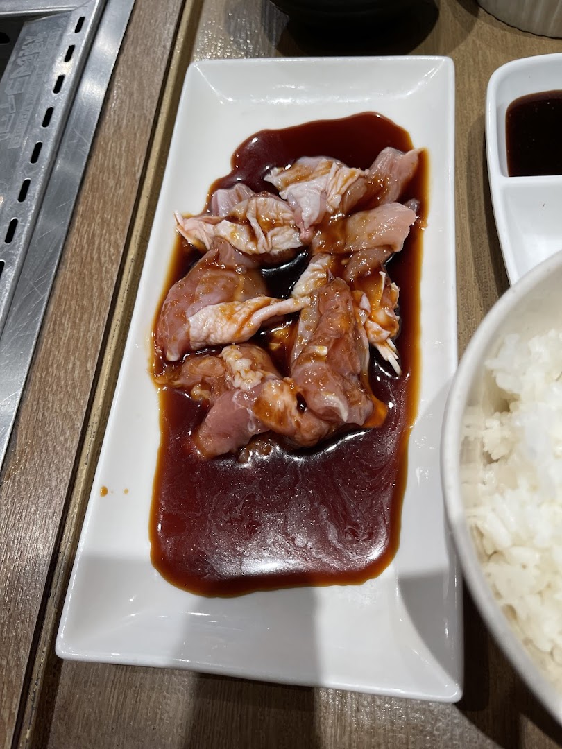 Marinated raw chicken pieces on a white plate, ready for grilling at a yakiniku restaurant.