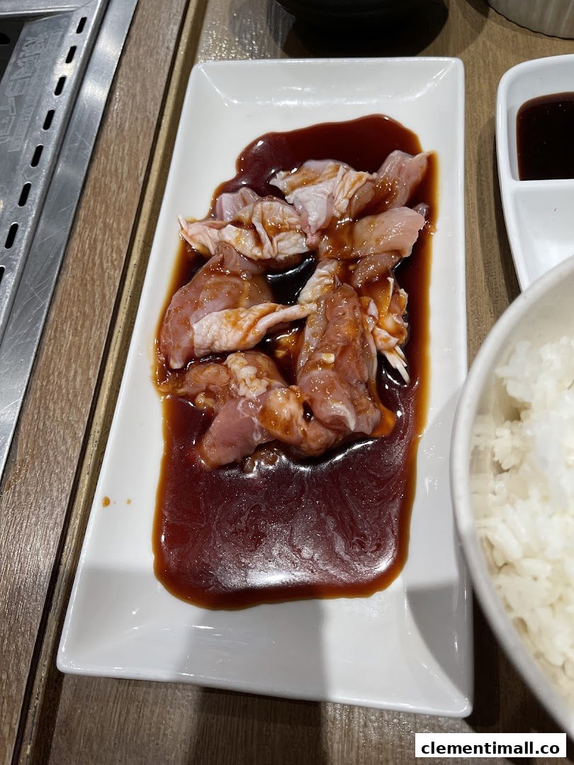 Marinated raw chicken pieces on a white plate, ready for grilling at a yakiniku restaurant.