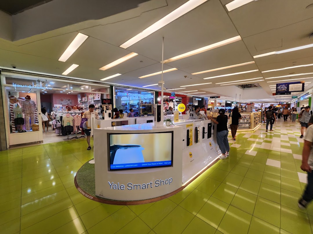 An interior view of a shopping mall featuring the Yale Smart Shop display kiosk with various smart home security products.