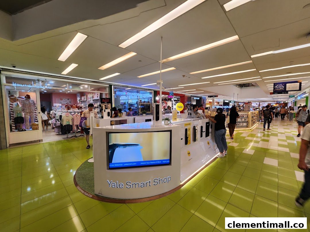 An interior view of a shopping mall featuring the Yale Smart Shop display kiosk with various smart home security products.