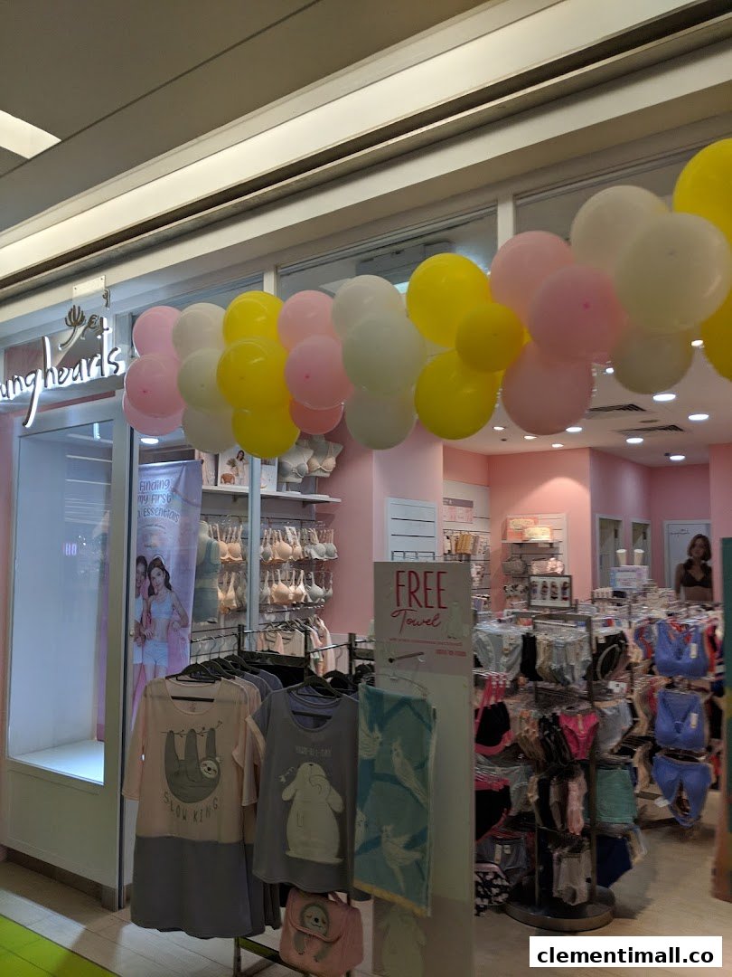 The Young Hearts shop entrance adorned with balloons, showcasing lingerie, sleepwear, and a 'Free Towel' promotion.
