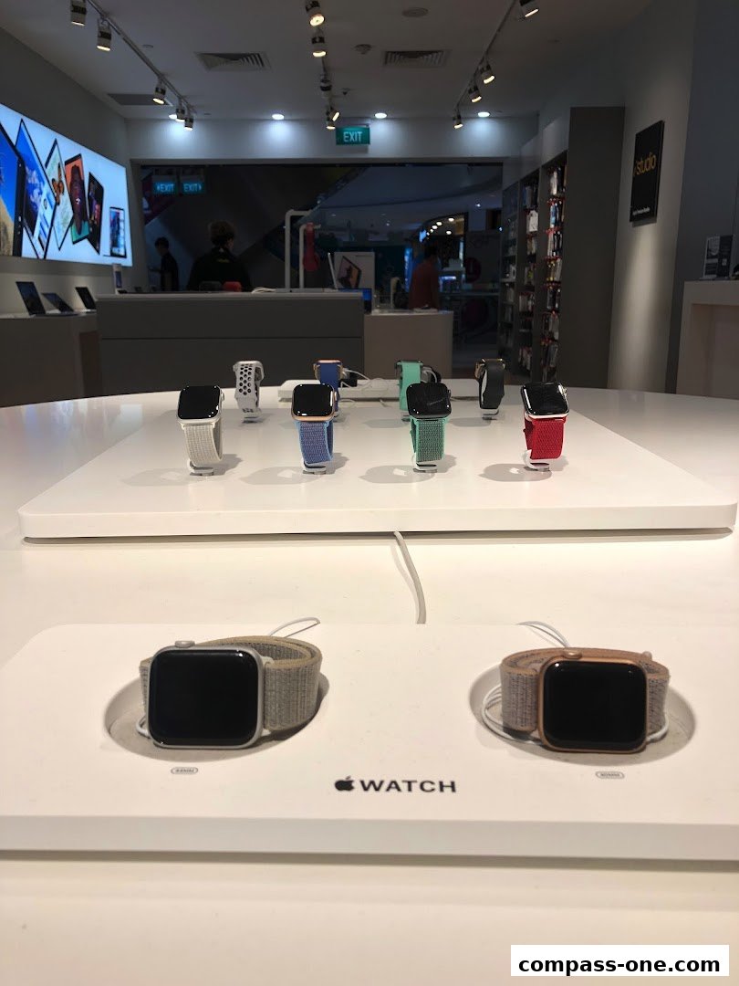 Display of Apple Watches with various colored bands on a white table in a store.