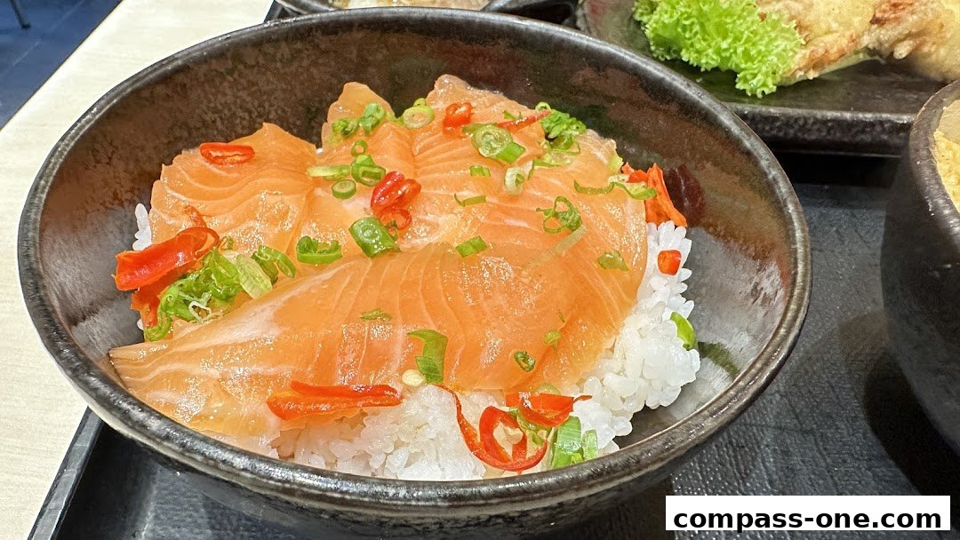 A close-up of a salmon donburi bowl with chili and spring onions.
