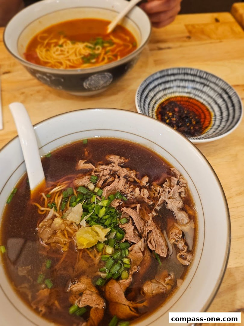 Two bowls of delicious noodle soup, one with beef and the other with a tomato-based broth.