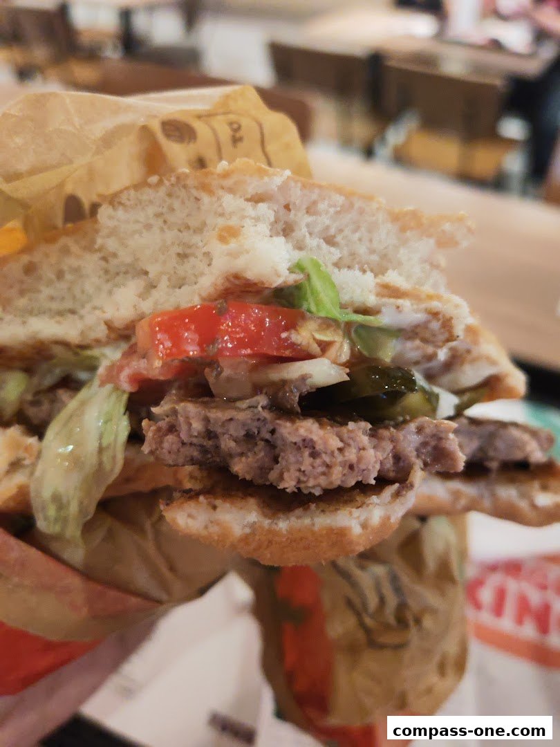 A close-up shot of a juicy burger with fresh toppings, held in hand.