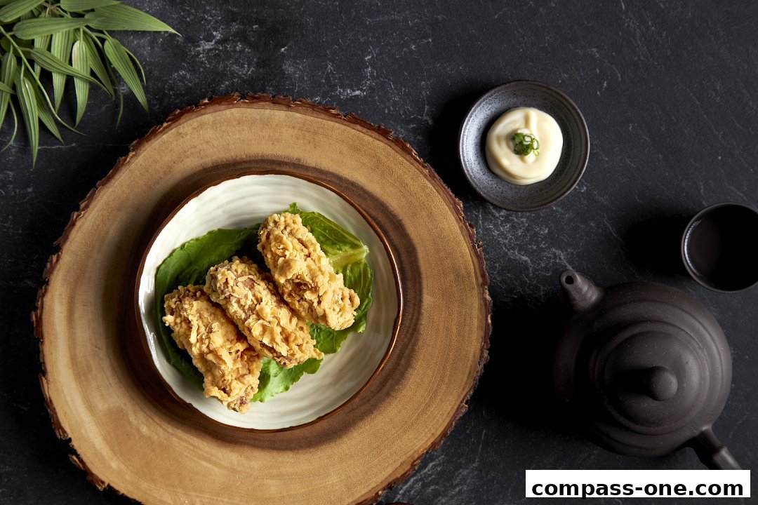 Crispy fried chicken wings served with dipping sauce and tea on a dark, textured surface.