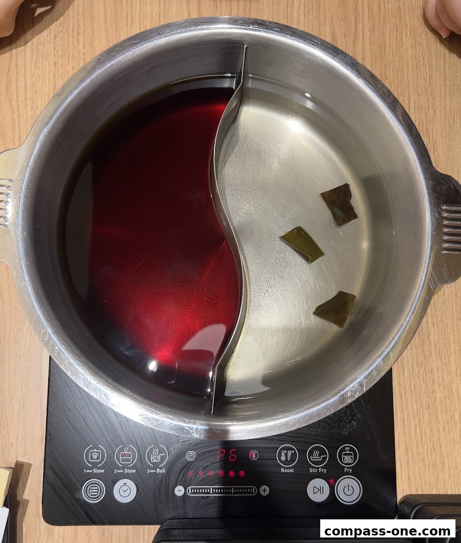 A split hot pot with two different broths and kombu on an induction cooker.