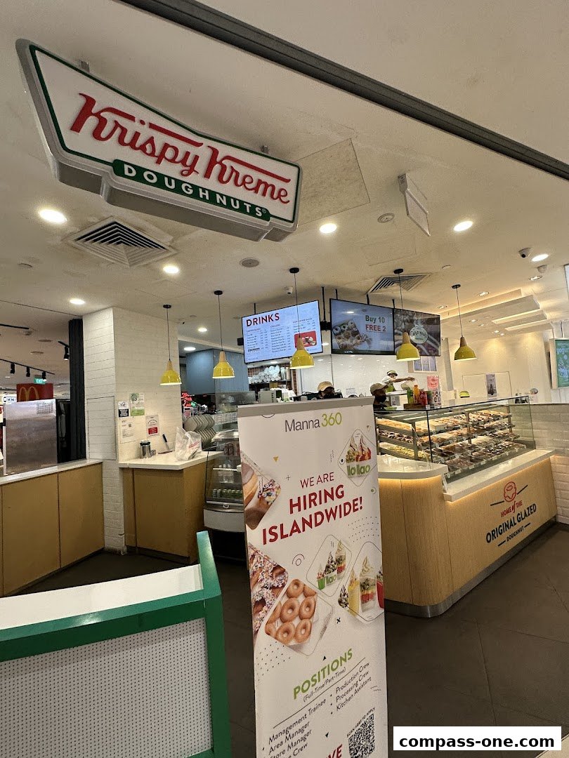Krispy Kreme doughnut shop interior with a display case full of donuts and a hiring banner.