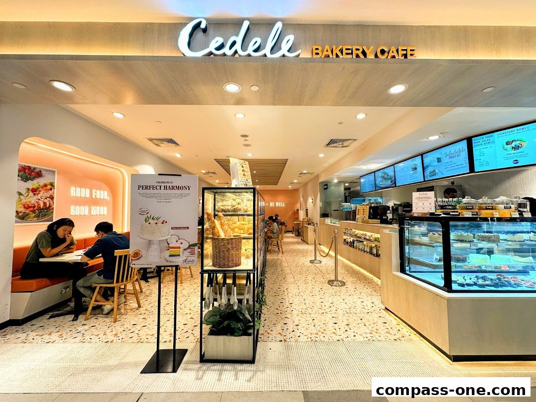 The inviting entrance of Cedele Bakery Cafe, showcasing a display of cakes and baked goods.