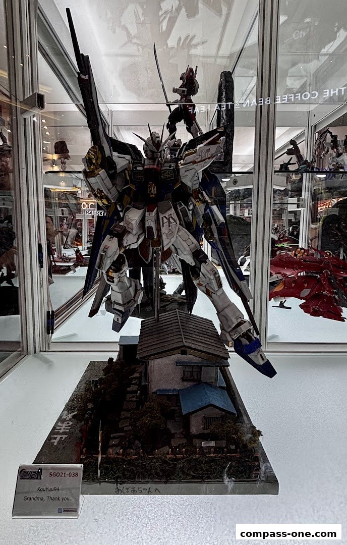 A detailed model of a white and blue robot standing in front of a diorama of a house.