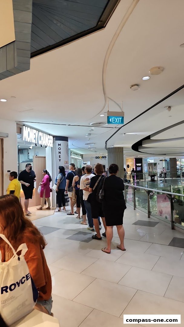 A queue of people waiting outside a money changer shop in a mall.