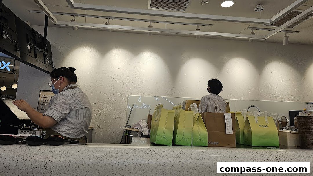Staff members working behind the counter at CHICHA San Chen, with takeaway bags ready.