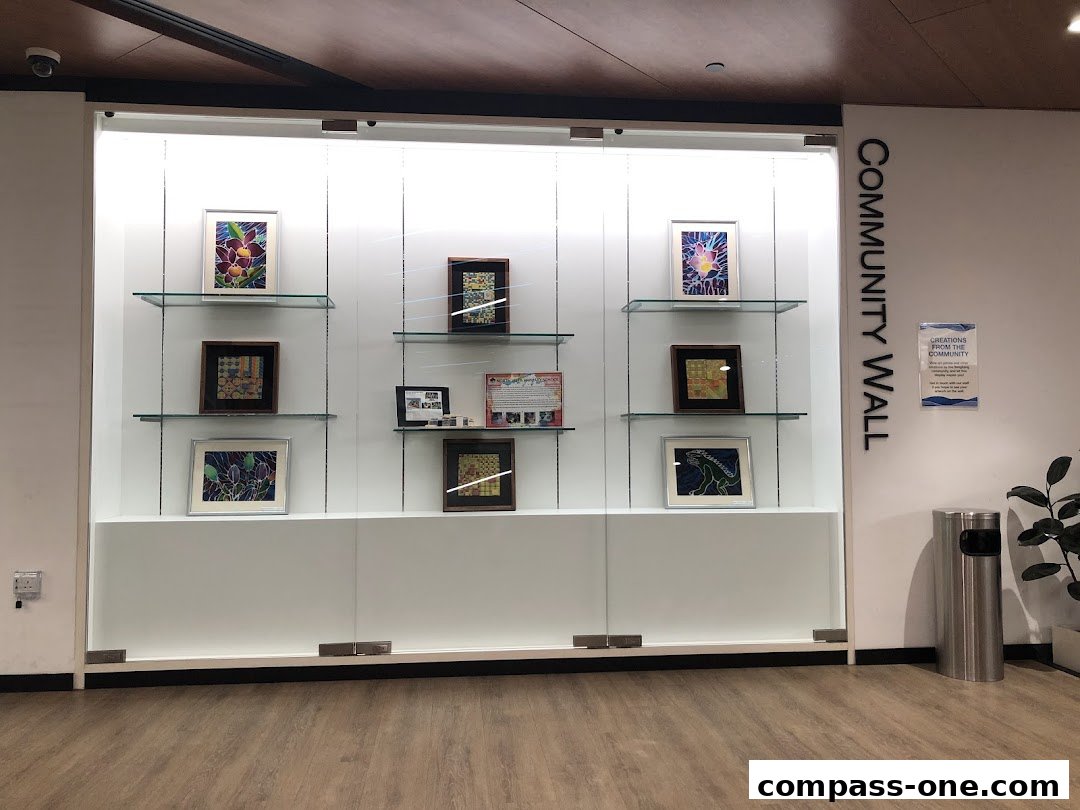 A display case showcasing framed artwork and photographs on shelves, labeled 'COMMUNITY WALL'.