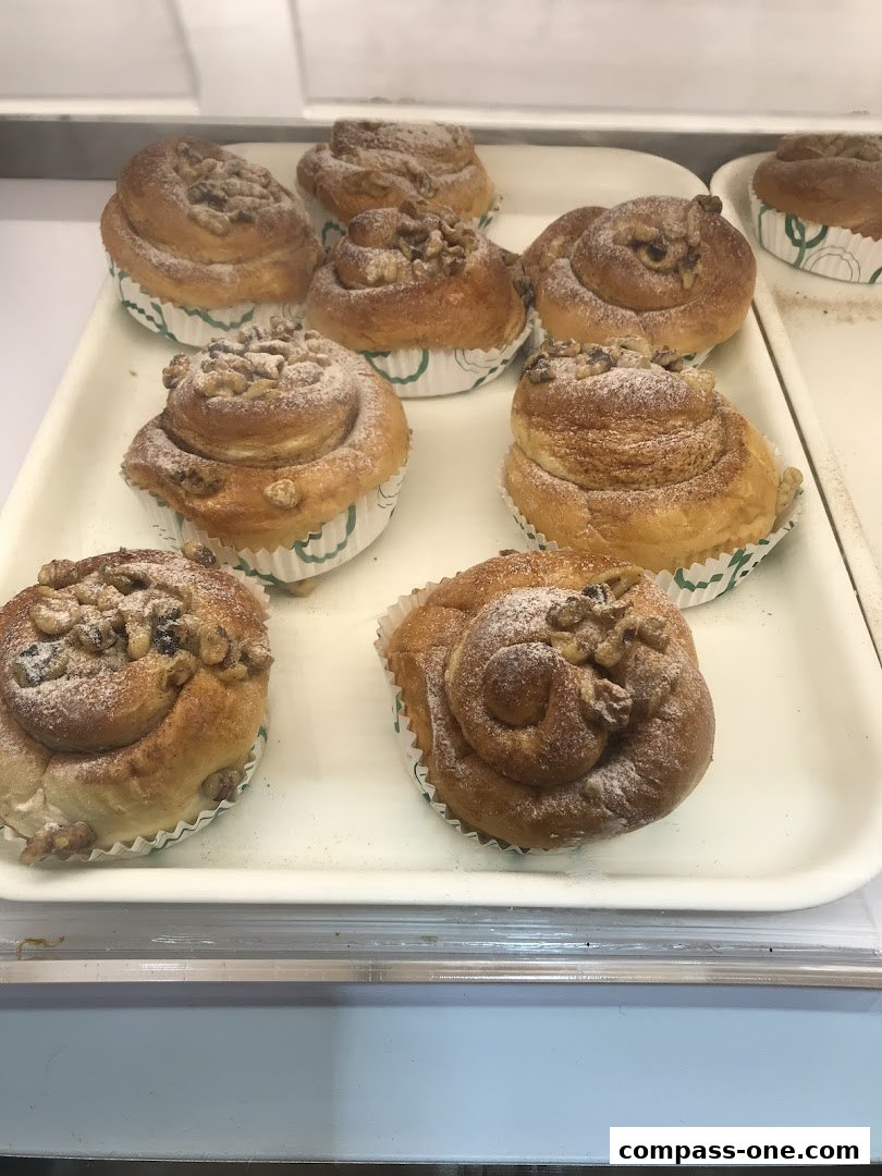A tray of freshly baked cinnamon rolls topped with walnuts and powdered sugar.