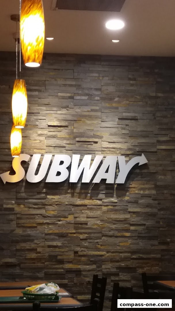 The Subway logo is displayed prominently on a stone-tiled wall with decorative lighting.