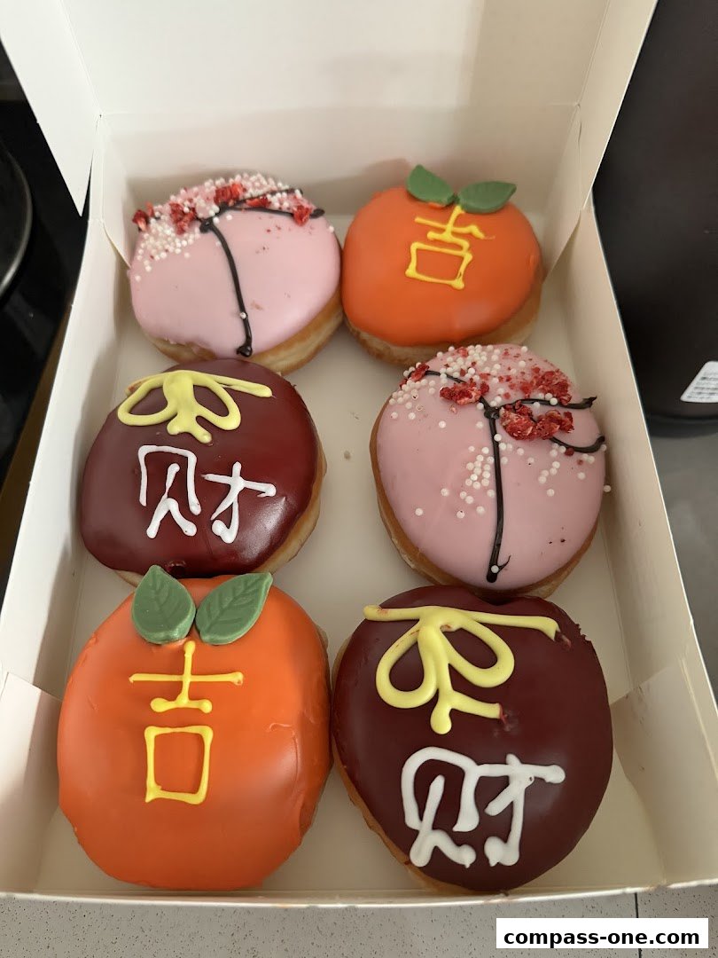 A box of six assorted Krispy Kreme donuts with festive Chinese New Year themed decorations.