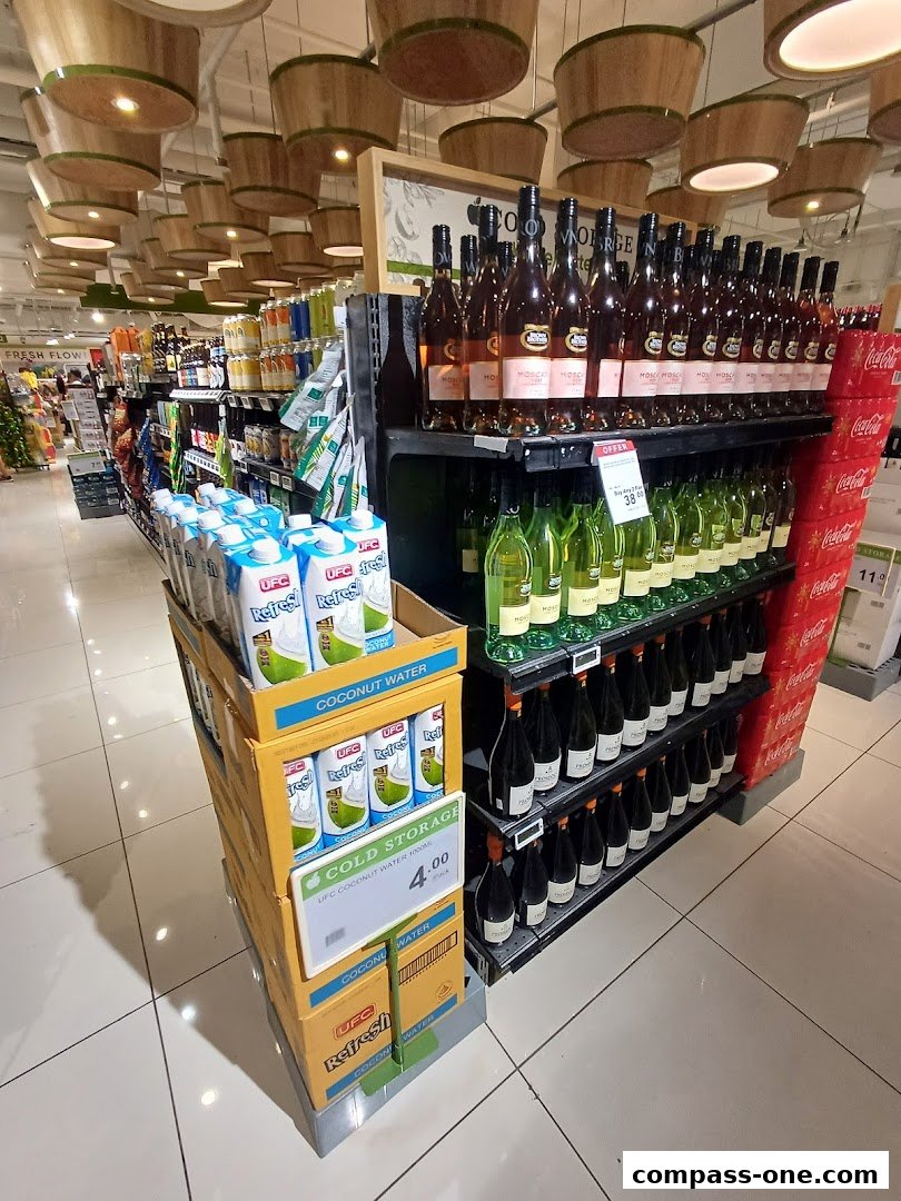 Aisle in a supermarket featuring rows of wine bottles and cartons of coconut water.