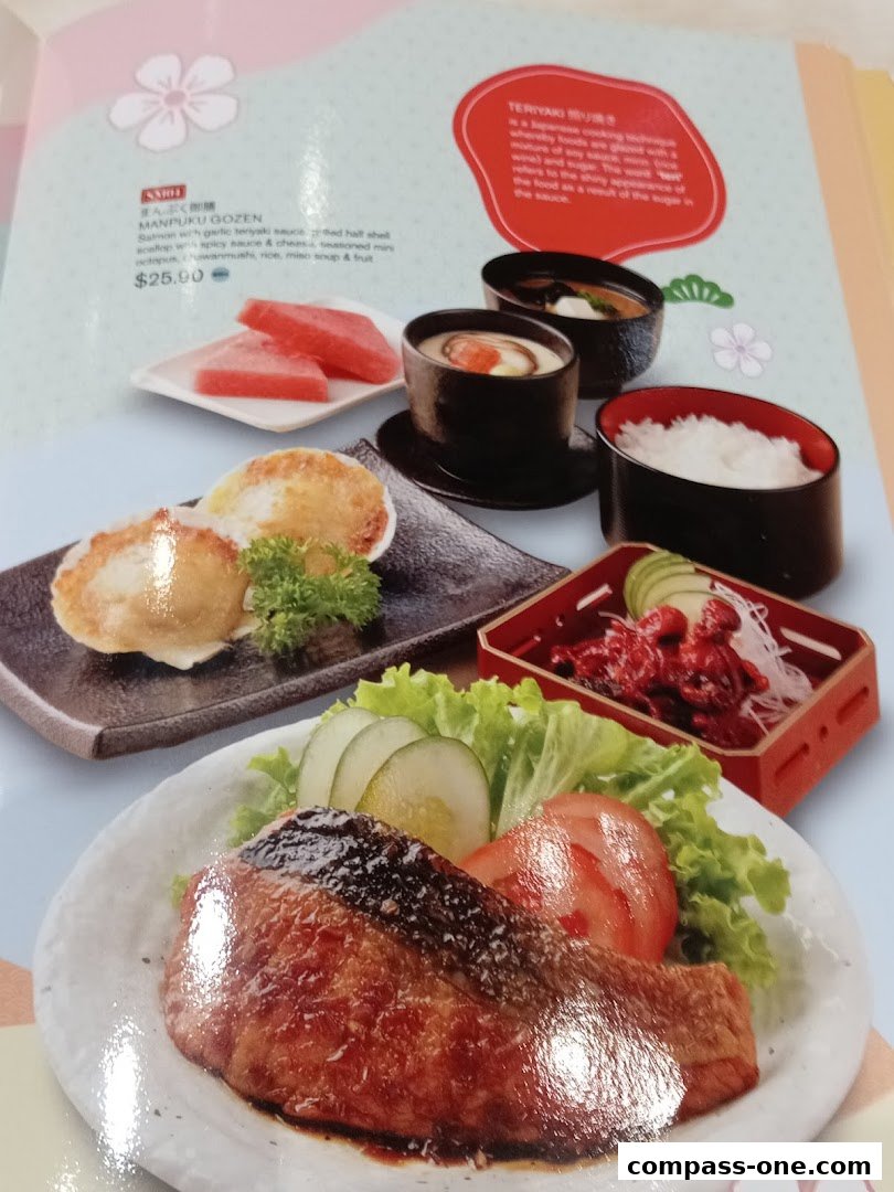A menu item featuring salmon with teriyaki sauce, rice, soup, and fruit.