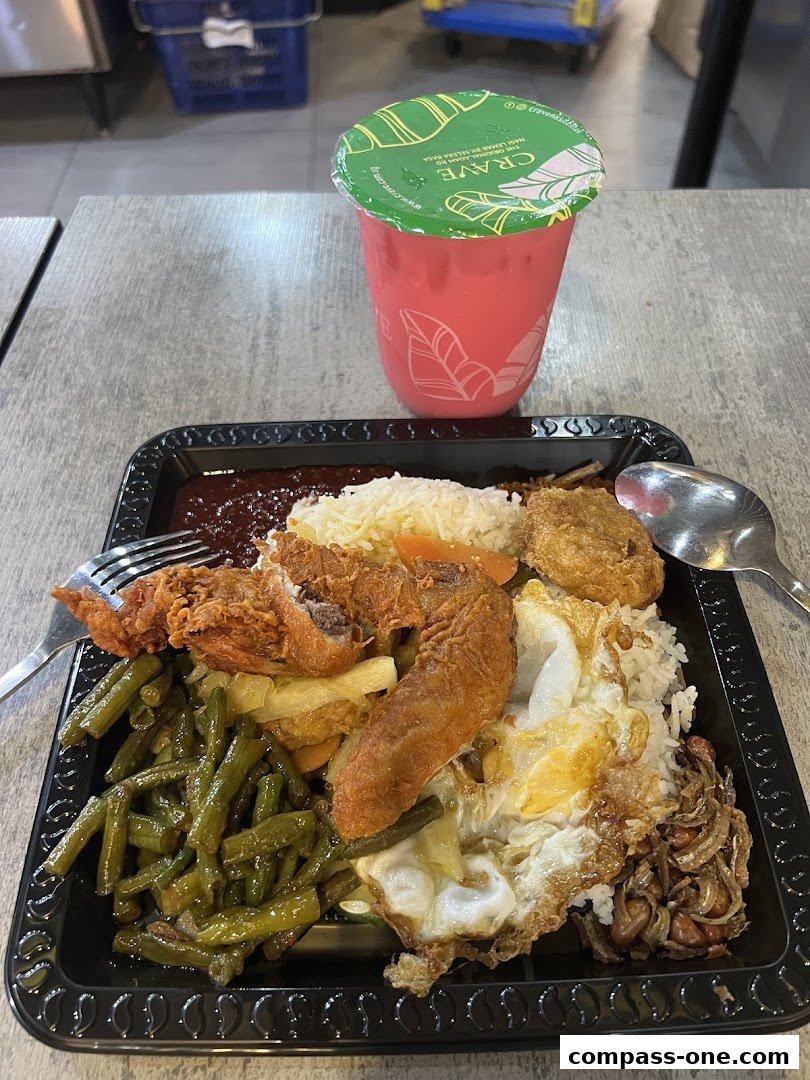 A plate of Nasi Lemak with fried chicken and a pink drink.