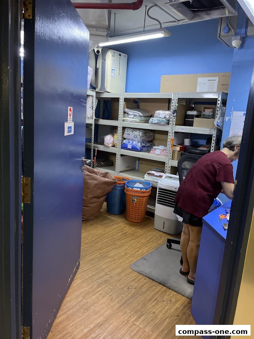 A person works at a counter in a laundry service shop with shelves of folded clothes.