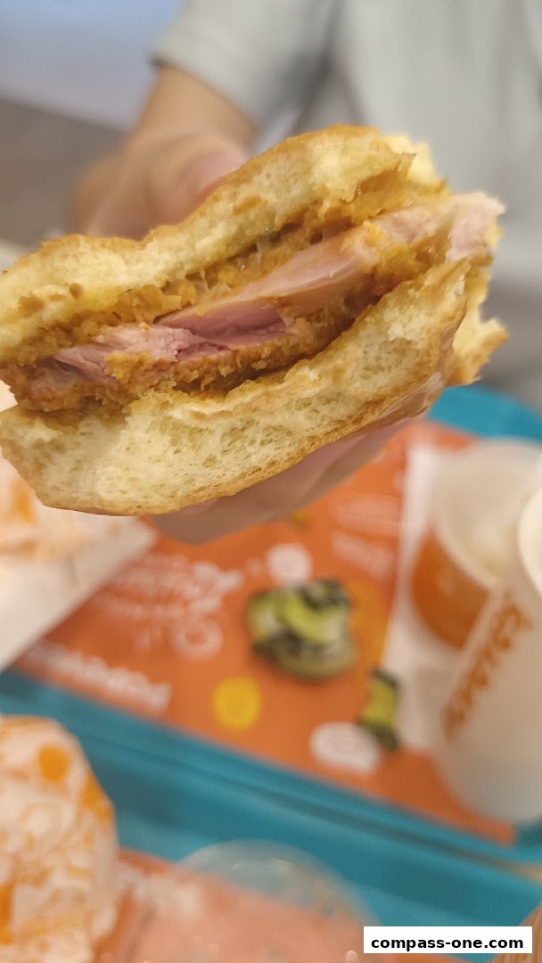 A close-up shot of a delicious Popeyes sandwich with crispy chicken and ham.