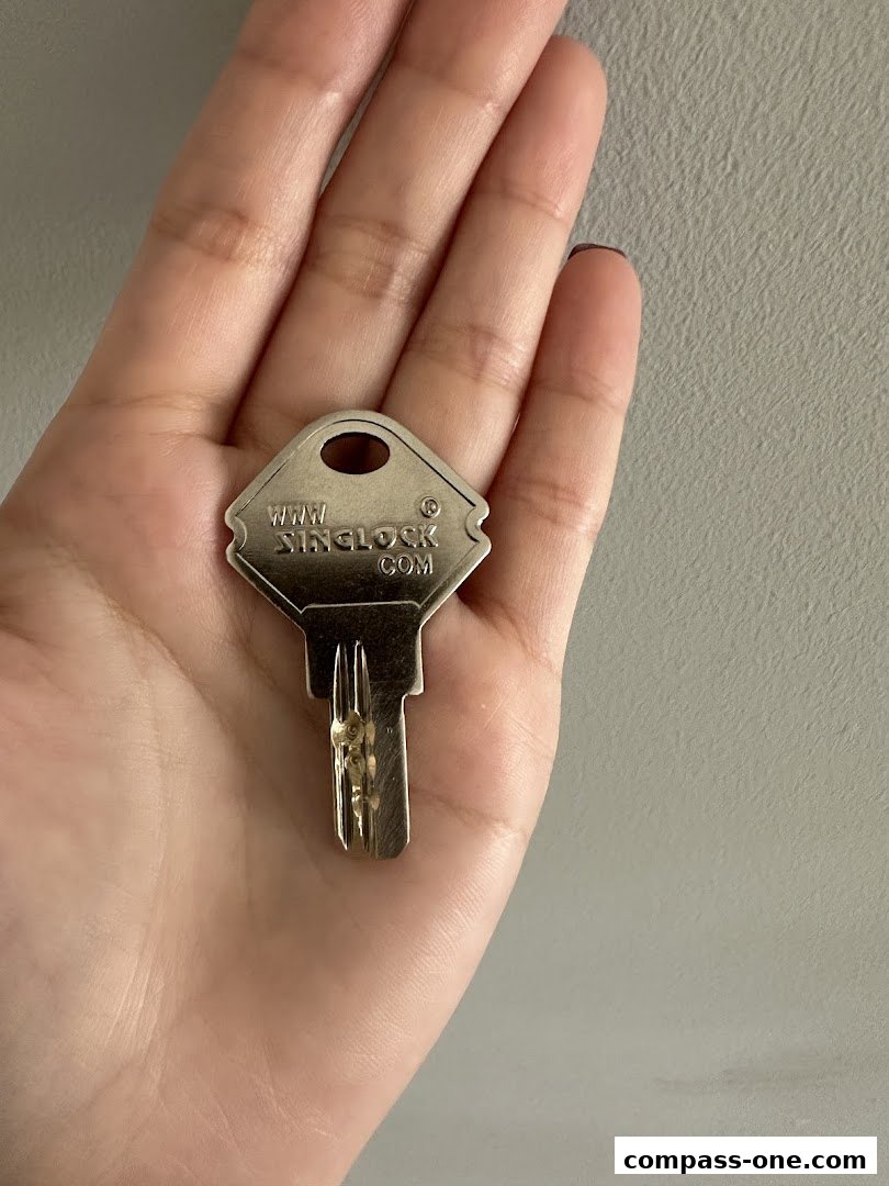 A hand holds a metal key with the website www.singlock.com engraved on it.