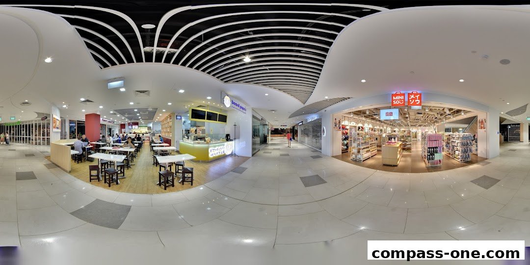 A wide view of a shopping mall corridor with shops and a cafe visible.