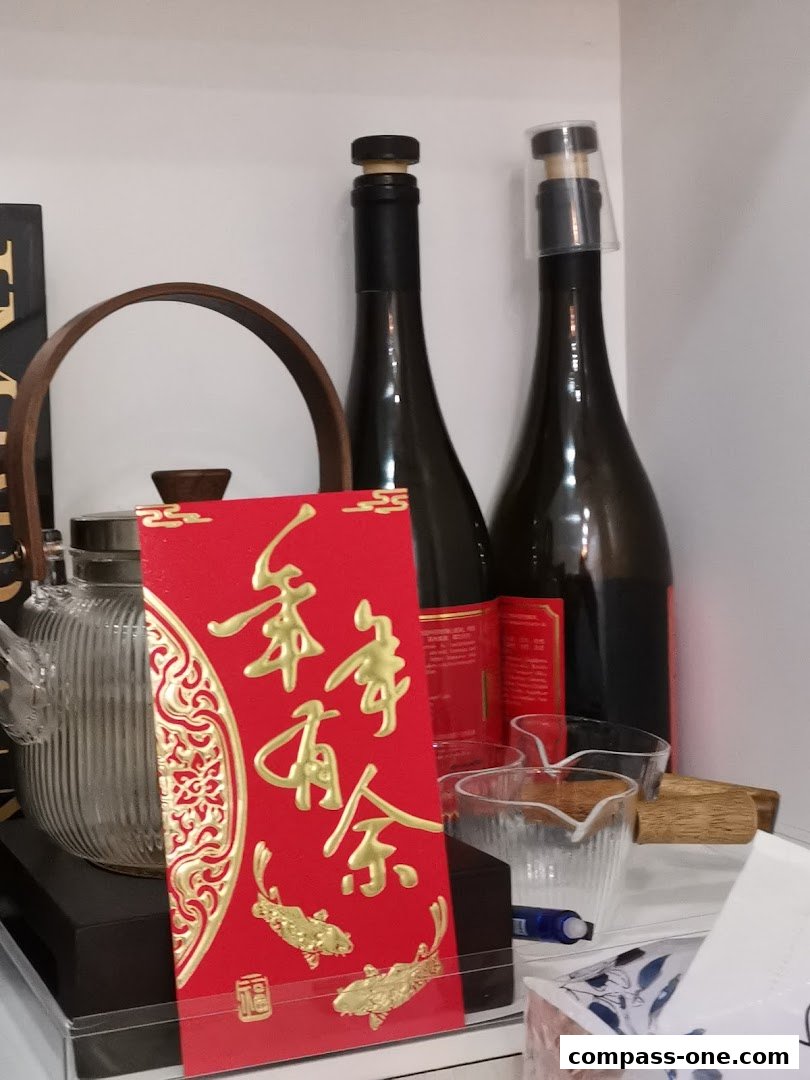 A red envelope with gold Chinese characters and koi fish, next to bottles and glasses.
