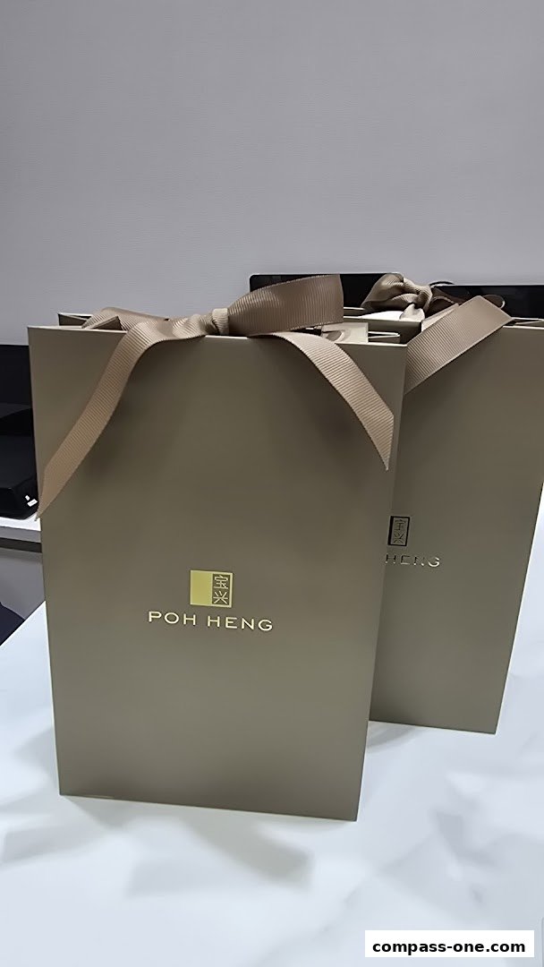 Two elegant gift bags from Poh Heng Jewellery, tied with satin ribbons.