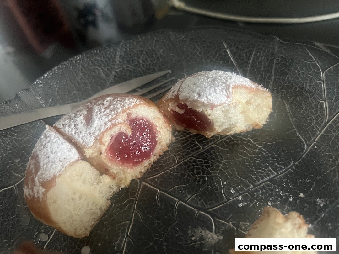 A close-up of a jam-filled pastry dusted with powdered sugar on a dark plate.