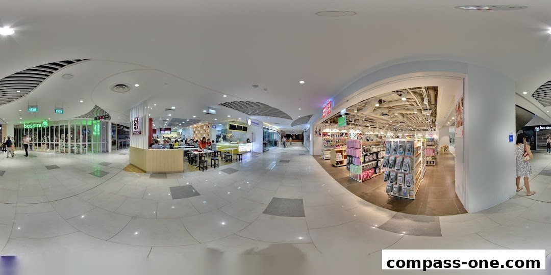 A wide view of a shopping mall interior with several shops and a food court area.