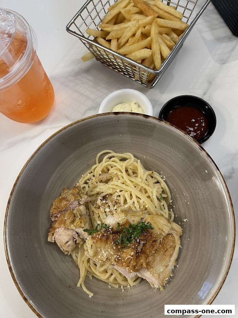 A bowl of spaghetti with chicken, fries, a drink, and dipping sauces.