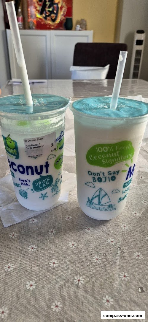 Two refreshing coconut shakes with straws on a table with a floral pattern.