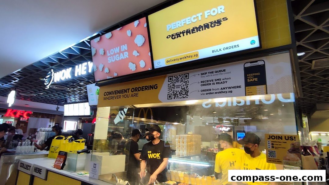 Wok Hey shop with staff preparing food and promotional screens above.
