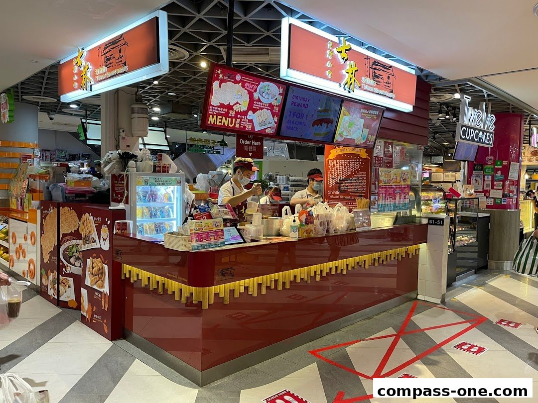 A Shihlin Taiwan Street Snacks stall with staff serving customers and various food displays.