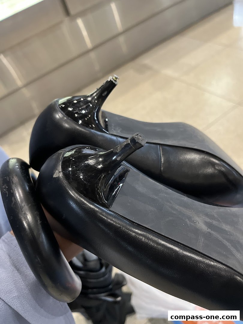 Close-up of damaged black high heels with broken heels being held.