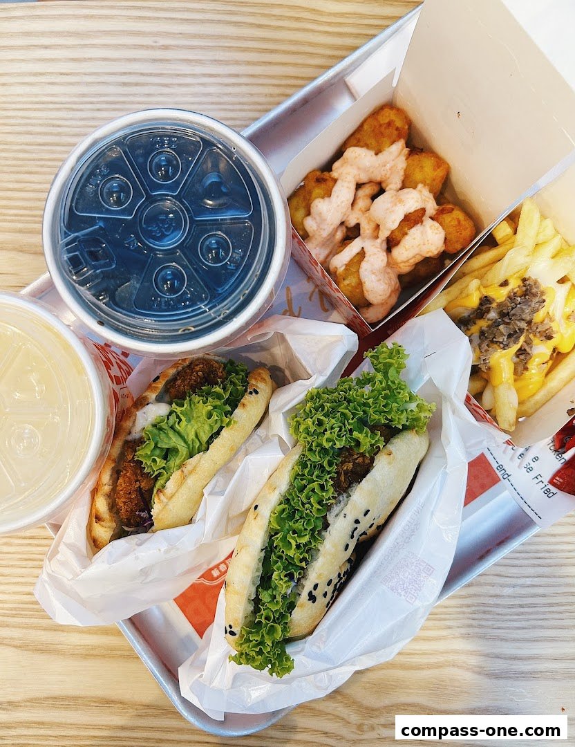 A tray of food from Shiok Burger featuring two hot dogs, loaded fries, tater tots, and drinks.