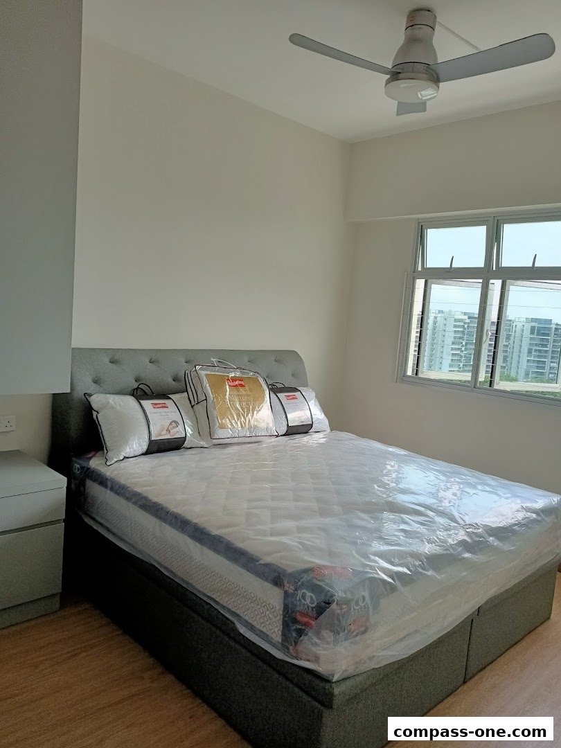 A bedroom with a new mattress and pillows on a bed, next to a nightstand, with a window view.